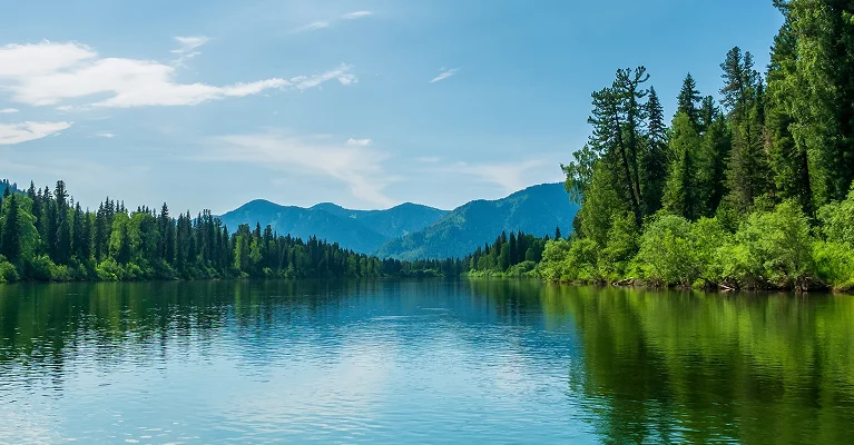 a lake with trees and mountains in the background
