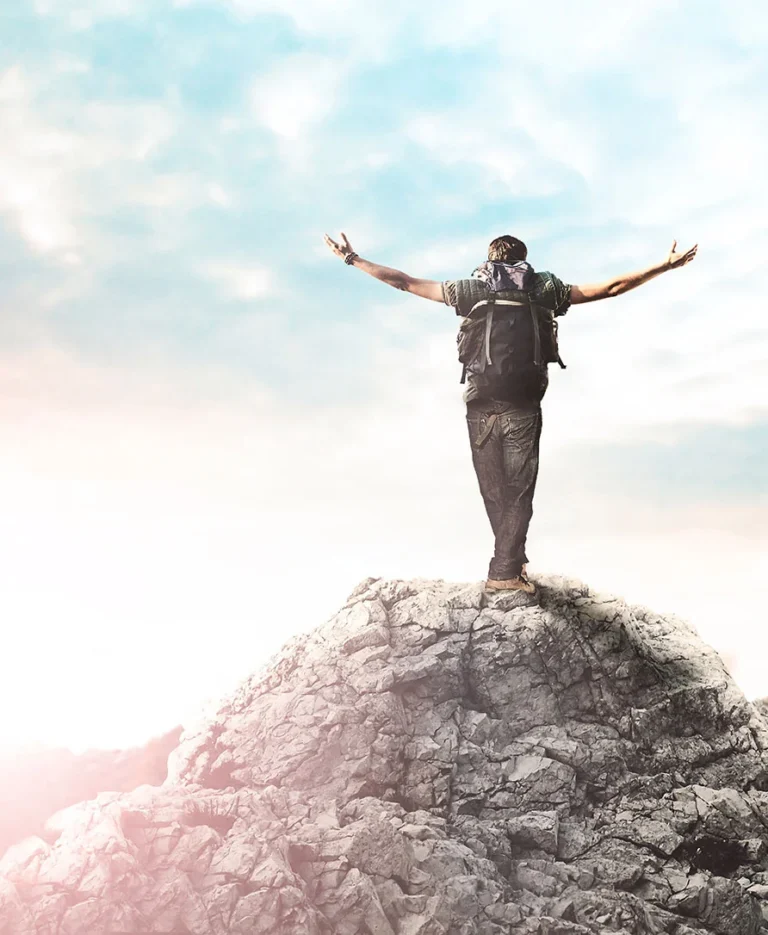 a person standing on a rock with arms outstretched